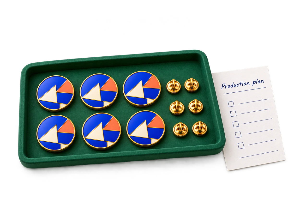 A tray of repeated enamel pin samples and a production planning sheet